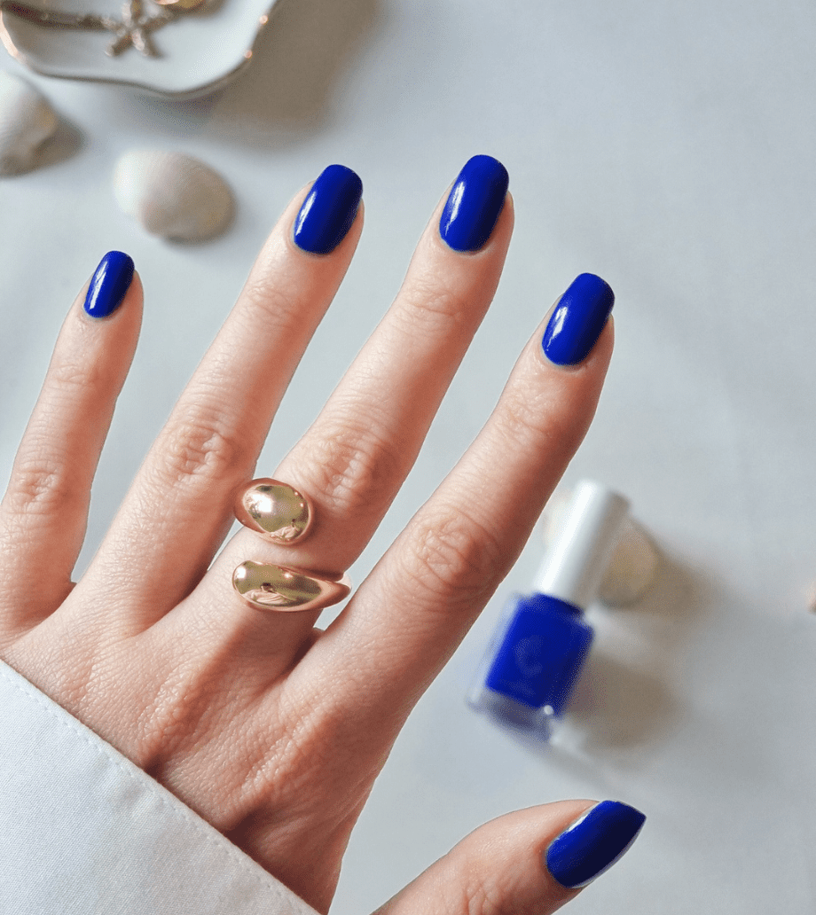 A hand wearing bright blue indie nail polish made in the UK
