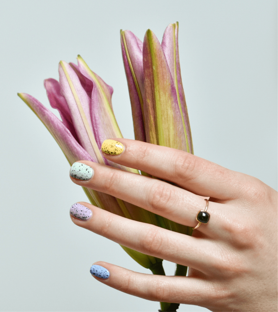 A hand wearing  indie nail polish holds lilies