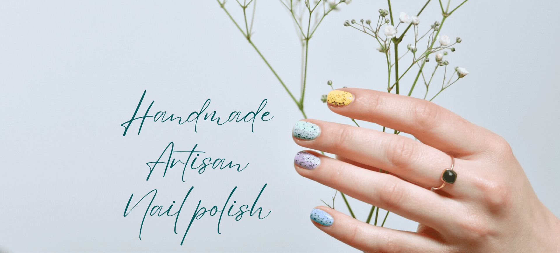 A hand wearing creme indie nail polish with black flakie topper holds a bunch of baby's breath flowers