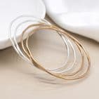 SILVER PLATED AND FAUX GOLD IRREGULAR FOUR BANGLE SET WITH WORN FINISH