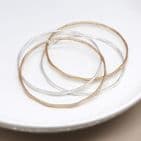 SILVER PLATED AND FAUX GOLD IRREGULAR FOUR BANGLE SET WITH WORN FINISH
