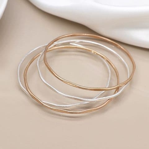 SILVER PLATED AND FAUX GOLD IRREGULAR FOUR BANGLE SET WITH WORN FINISH
