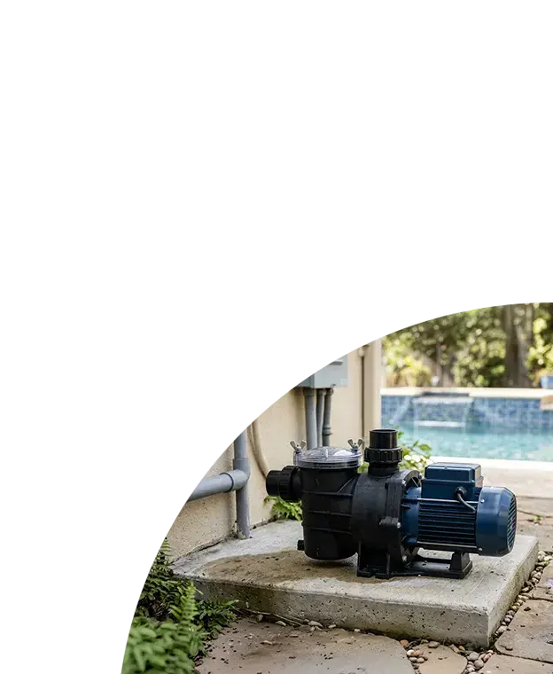A close up of an industrial swimming pool circulation pump on concrete, with a modern residential pool in the background.