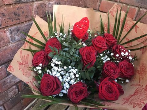 12 top quality red roses in hand tied
