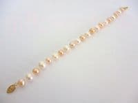 White and pink pearl bracelet with golden filigree clasp.