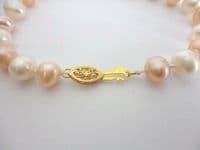 White and pink pearl bracelet with golden filigree clasp.