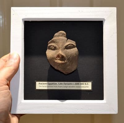 A pleasantly mounted facial segment from a large Ancient Egyptian wooden votive statuette. SOLD