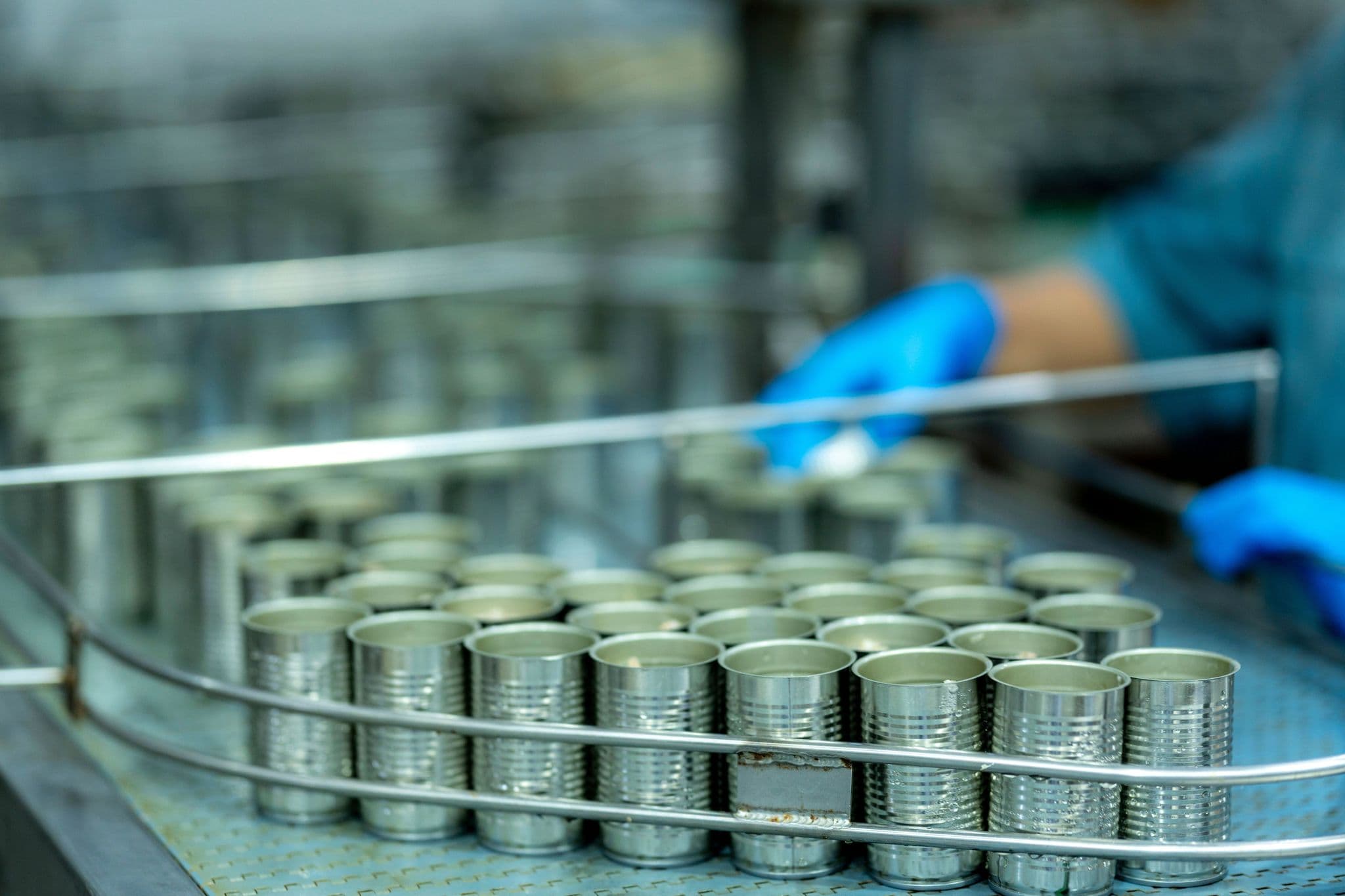 Open-top tin cans arranged on a production line, showing standard food-can formats prior to repurposing.