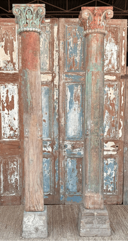 pair of 19th century teak pillars with faded paint tones, carved capitols and sandstone bases