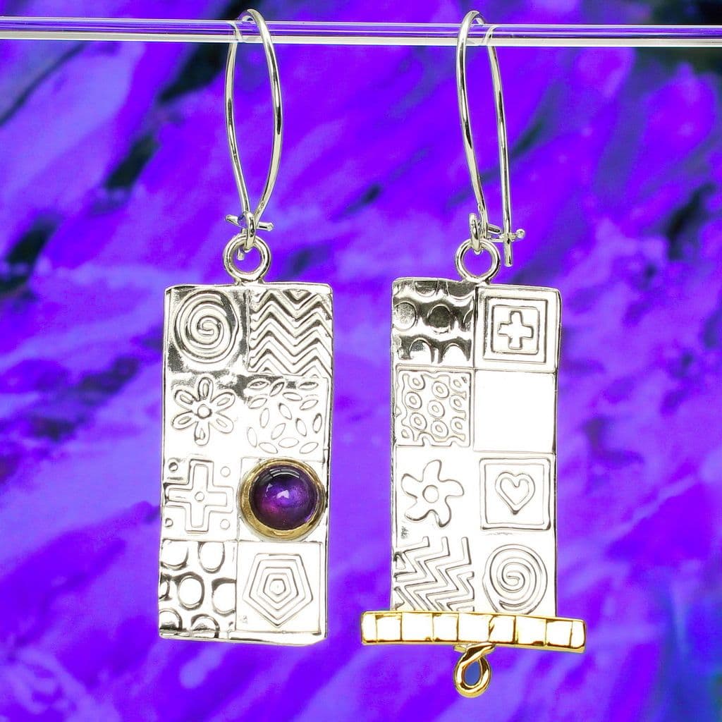 Sterling silver asymmetrical earrings featuring a amethyst gemstone and embossed shapes and symbols