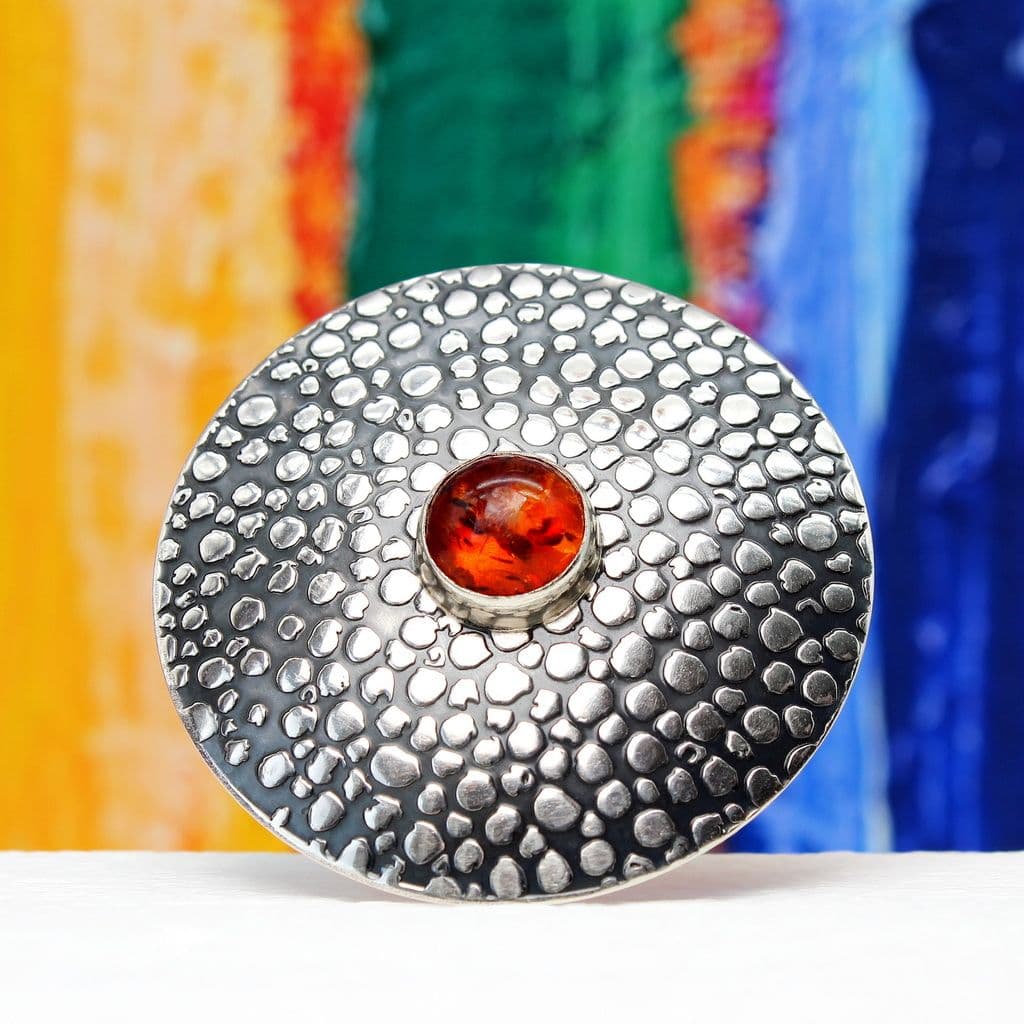 A large circular sterling silver brooch featuring a 10mm Amber stone and a shagreen embossed pattern