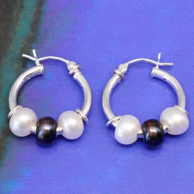 Freshwater pearl silver hoop earrings featuring white and peacock blue/black pearls.