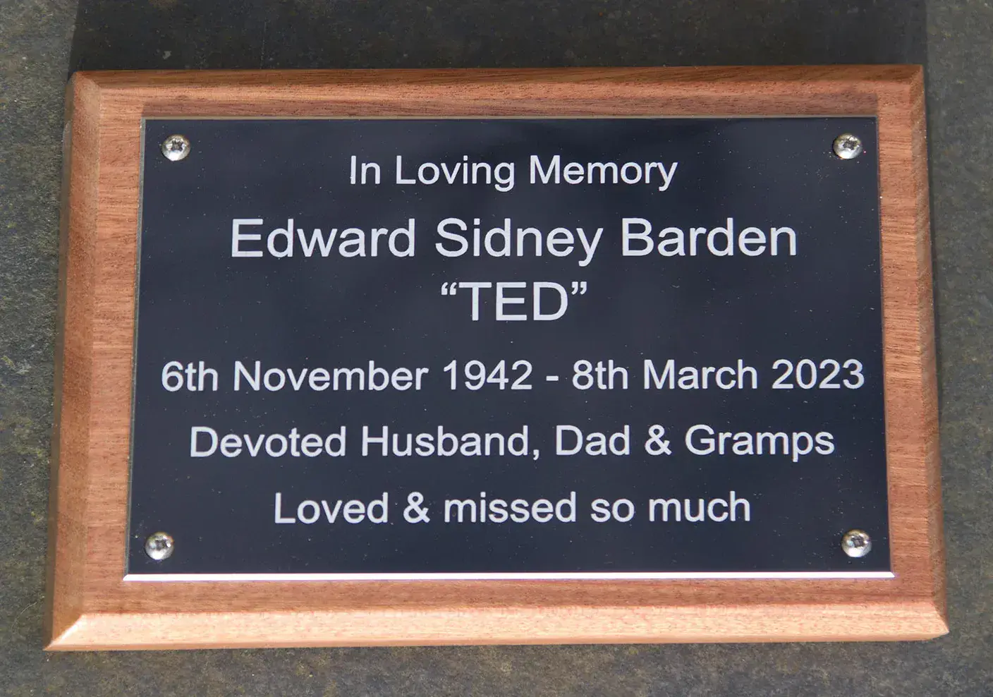 Black aluminium plaque on backing board with a 45 degree angle edge.